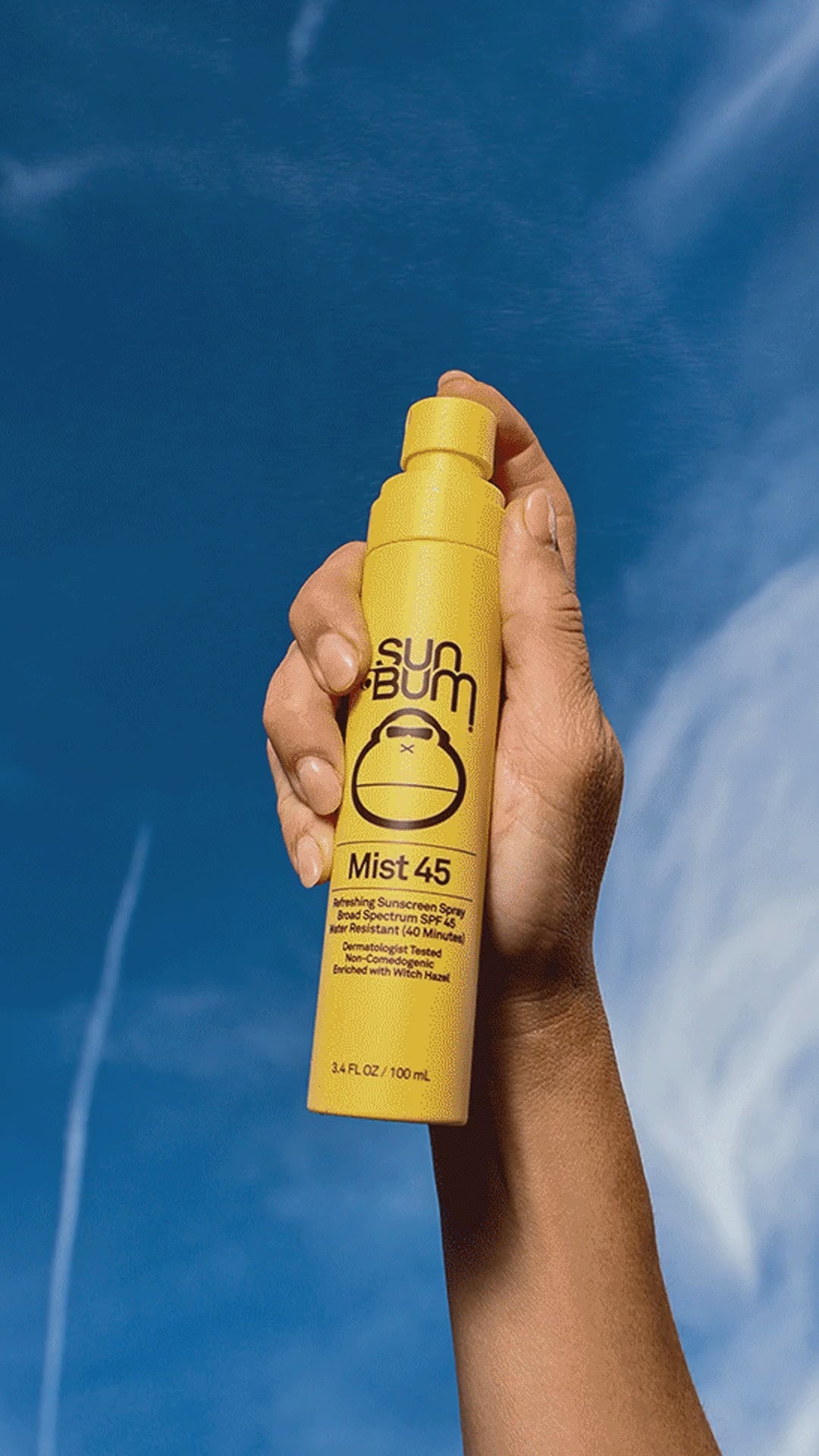 Person holding Sun Bum Mist 45 with blue sky background