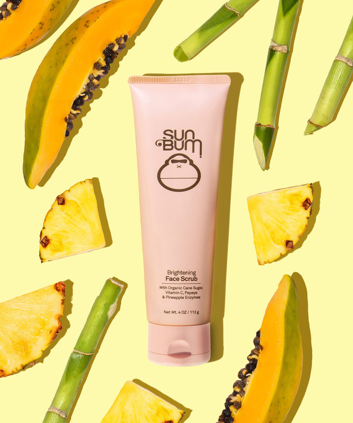 Brightening Face Scrub with Papaya & Pineapple Enzymes by Sun Bum, displayed with fresh fruit slices and organic cane sugar.